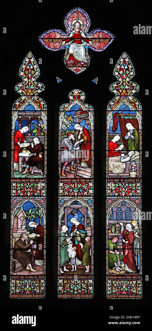Ein Buntglasfenster von Frederick Preedy mit Darstellungen von Acts of Mercy, St. Andrew's Church, Cleeve Prior, Worcestershire Stockfoto