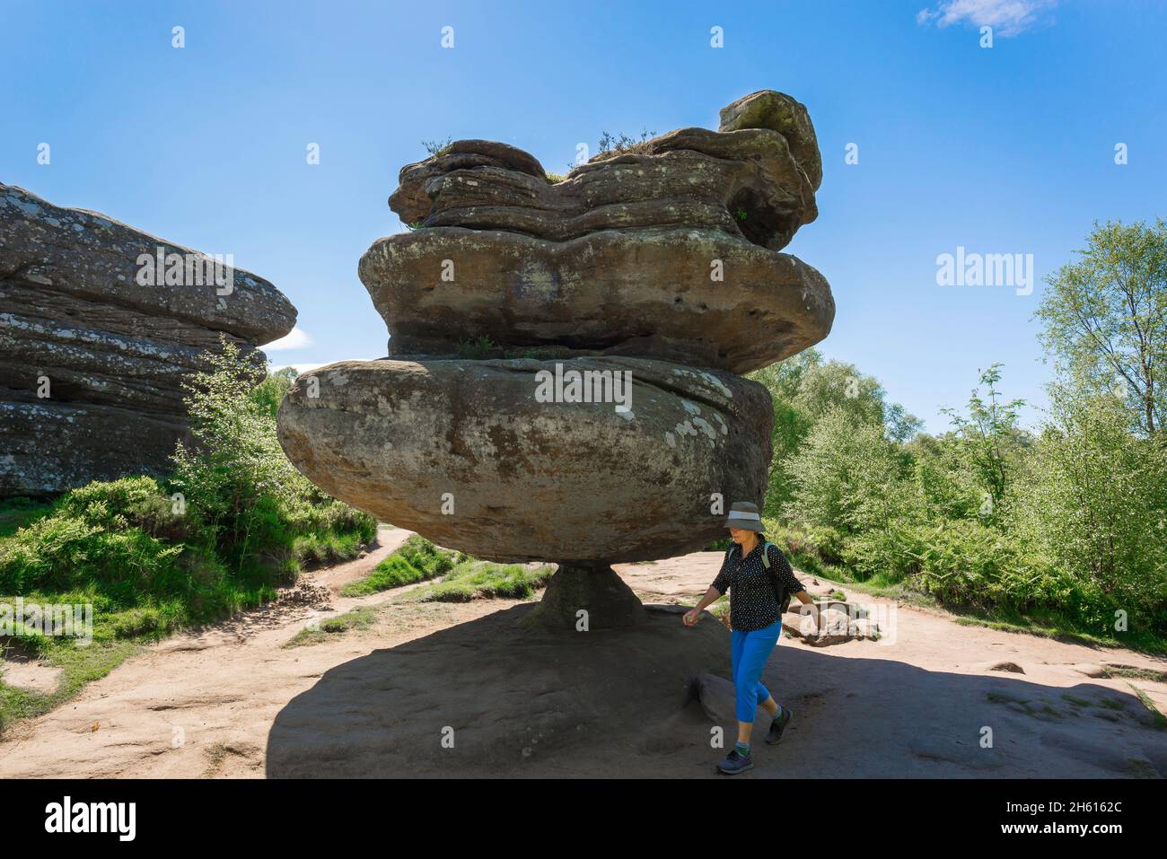 Wanderfrau, Blick auf eine reife Wanderin, die am Idol Rock, einer dramatischen Felsformation in Brimham Rocks, North Yorkshire National Park, England, spazieren geht Stockfoto