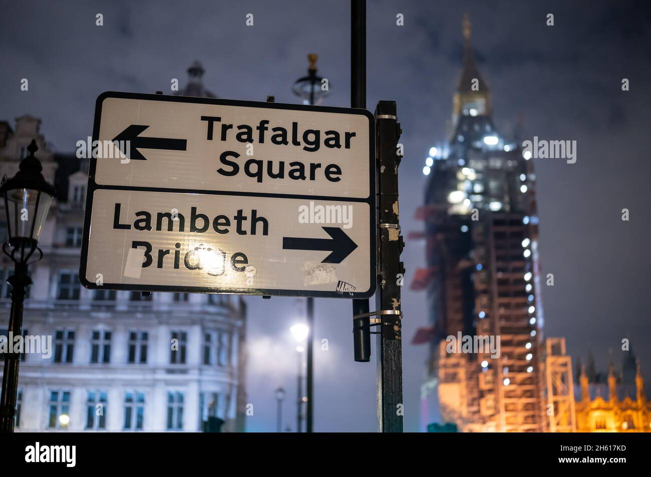 LONDON - 1. NOVEMBER 2021: Richtungsschild mit den Houses of Parliament in der Nacht im Hintergrund Stockfoto