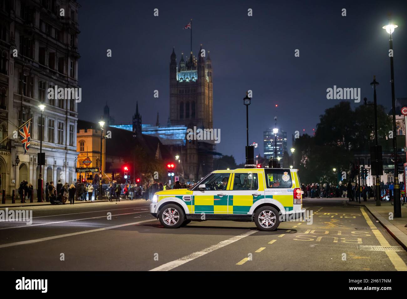 LONDON - 1. NOVEMBER 2021: Sanitäter im Geländewagen wartet mit Demonstranten und Parlamentsgebäuden im Hintergrund auf den Millionen-Maskenmarsch Stockfoto