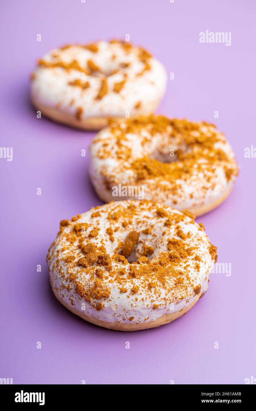 Süßer glasierter Donut mit Streuseln auf violettem Hintergrund. Stockfoto
