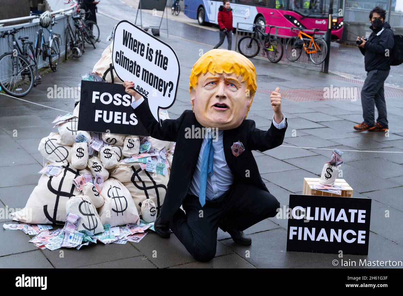 Glasgow, Schottland, Großbritannien. November 2021. Tag dreizehn und letzter Tag des UN-Klimagipfels COP26 in Glasgow. Boris Johnson Bildnis steht neben Säcken mit Geld, das bei einem Protest vor dem Veranstaltungsort der COP26 aus der Gewinnung fossiler Brennstoffe gewonnen wurde. Der Protest wurde von Avaaz organisiert, einer US-Wohltätigkeitsorganisation, die sich für den globalen Aktivismus im Klimawandel einsetzt. Iain Masterton/Alamy Live News. Stockfoto