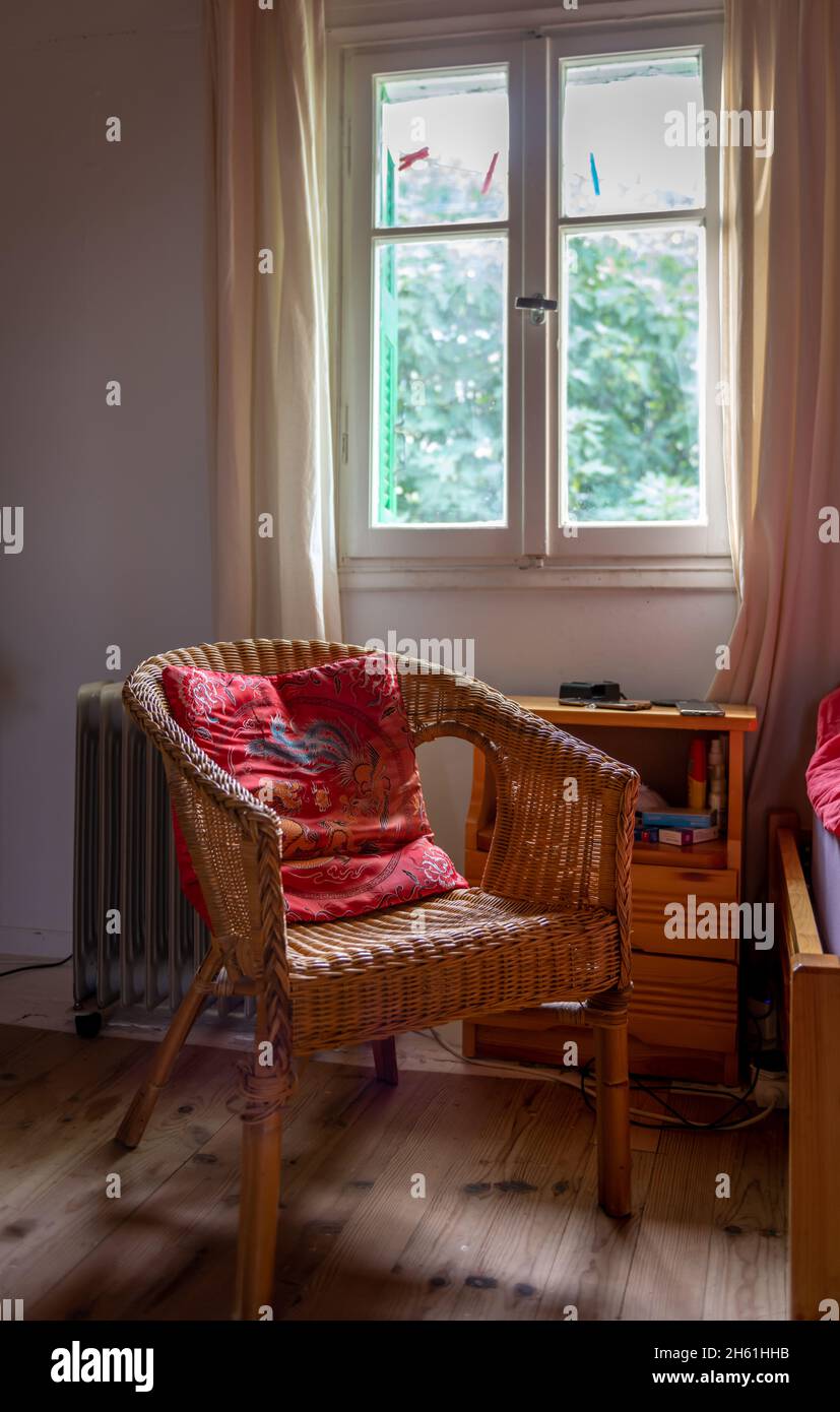 Ein gemütliches, gemütliches, warmes Interieur mit einem bequemen Stuhl am Fenster zur Entspannung. Stockfoto