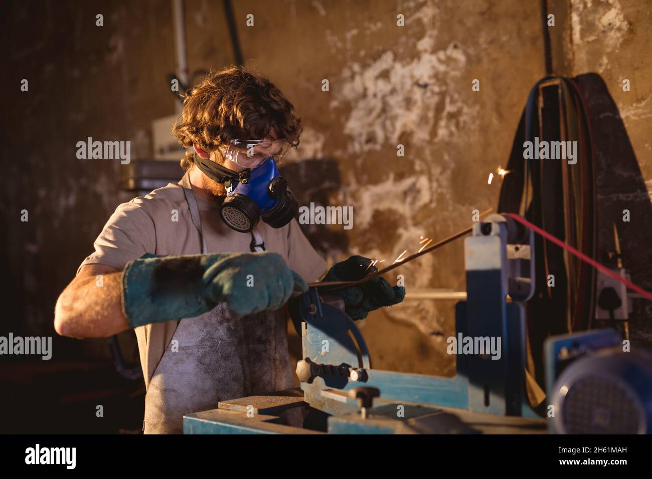 Schmied trägt Gasmaske bei der Arbeit an Maschinen in der Metallindustrie Stockfoto