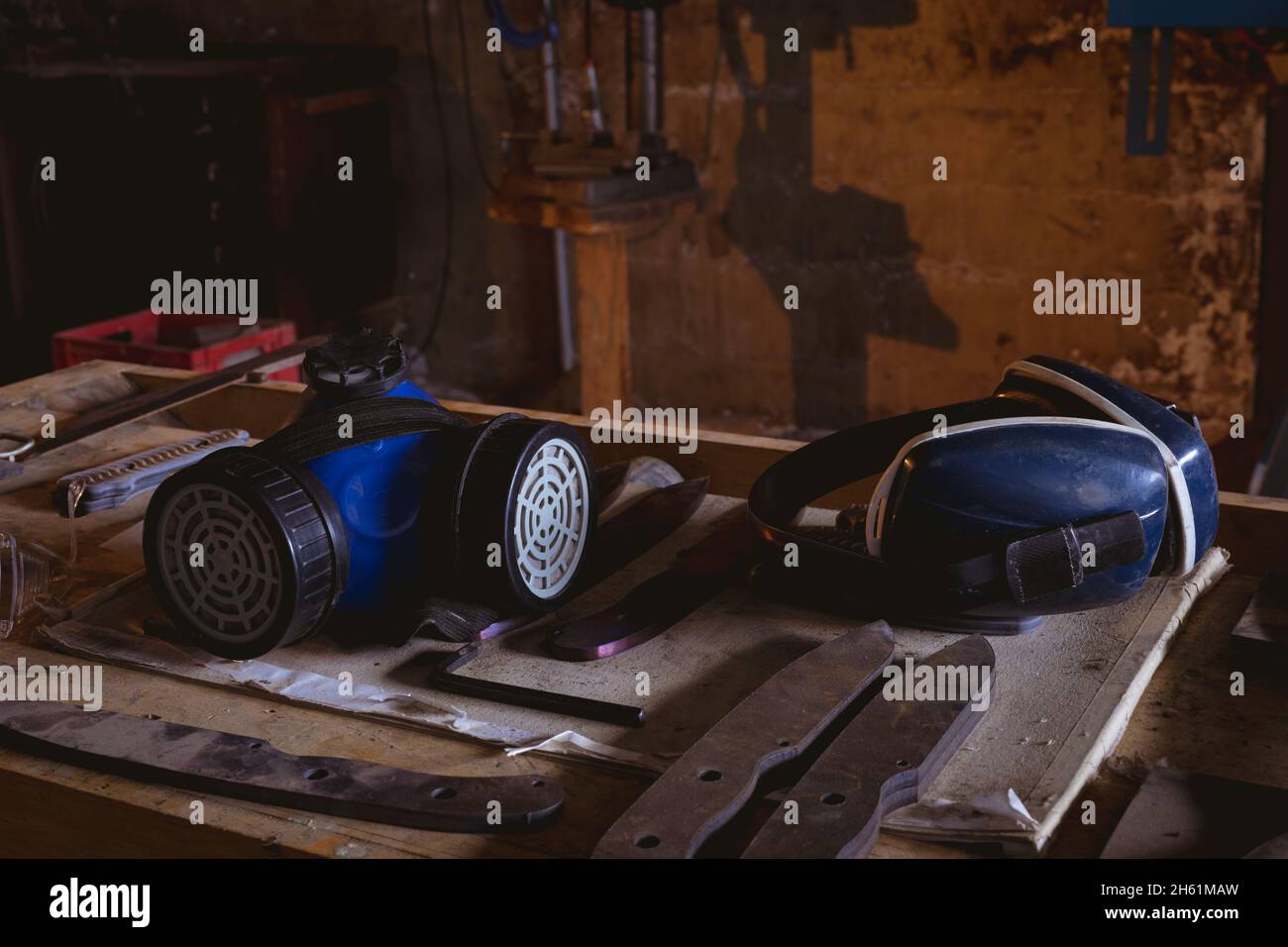 Gasmaske mit Ohrschutz und Metall auf der Werkbank in der Fertigungsindustrie Stockfoto