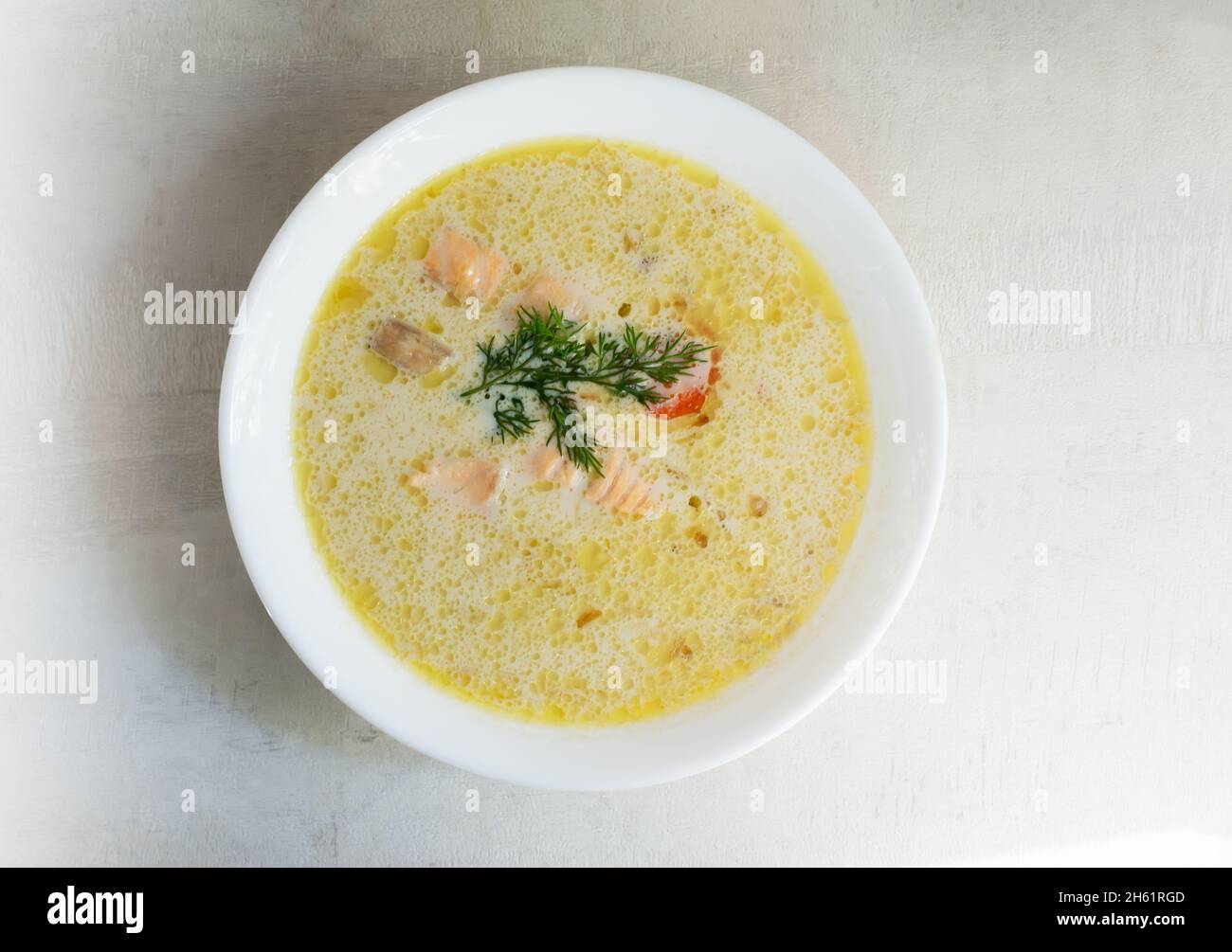 Lachs- und Cremefischsuppe in einer weißen Schüssel mit einem Dill-Zweig. Lohikeitto ist eine traditionelle finnische und karelische Suppe. Draufsicht. Stockfoto