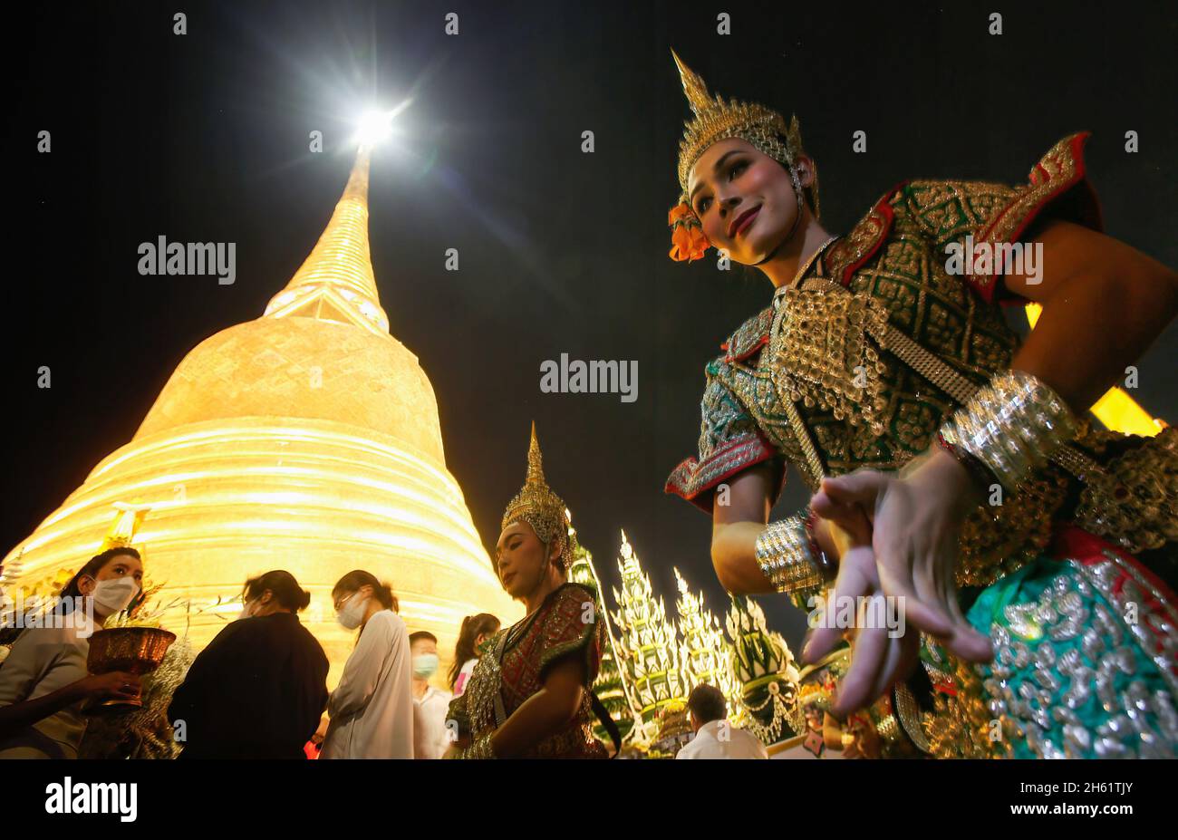 Bangkok, Thailand. November 2021. Eine Tänzerin tritt vor dem Tempel Wat Saket auf, der während des Tempels auch als Goldener Berg bekannt ist und den goldenen Berg mit rotem Tuch umwickelt. Eifrige Anhänger versammelten sich, um den Chedi des Goldenen Berges mit einem heiligen roten Tuch zu umwickeln, was den Beginn des Wat Saket-Festivals markierte. Bevor sich die Gläubigen zu einer multikulturellen Parade anstellten, die aus Löwentänzern, traditionellen thailändischen Tänzern, Studenten der Tempelschule und spirituellen Brahmanen bestand. Namen von Familien und Angehörigen wurden in der Hoffnung, ein gutes Fortu zu erreichen, auf die über hundert Meter lange Strecke geschrieben Stockfoto