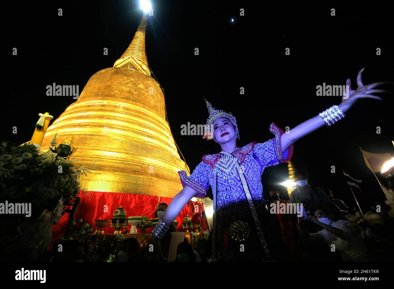 Bangkok, Thailand. November 2021. Eine Tänzerin tritt vor dem Tempel Wat Saket auf, der während des Tempels auch als Goldener Berg bekannt ist und den goldenen Berg mit rotem Tuch umwickelt. Eifrige Anhänger versammelten sich, um den Chedi des Goldenen Berges mit einem heiligen roten Tuch zu umwickeln, was den Beginn des Wat Saket-Festivals markierte. Bevor sich die Gläubigen zu einer multikulturellen Parade anstellten, die aus Löwentänzern, traditionellen thailändischen Tänzern, Studenten der Tempelschule und spirituellen Brahmanen bestand. Namen von Familien und Angehörigen wurden in der Hoffnung, ein gutes Fortu zu erreichen, auf die über hundert Meter lange Strecke geschrieben Stockfoto