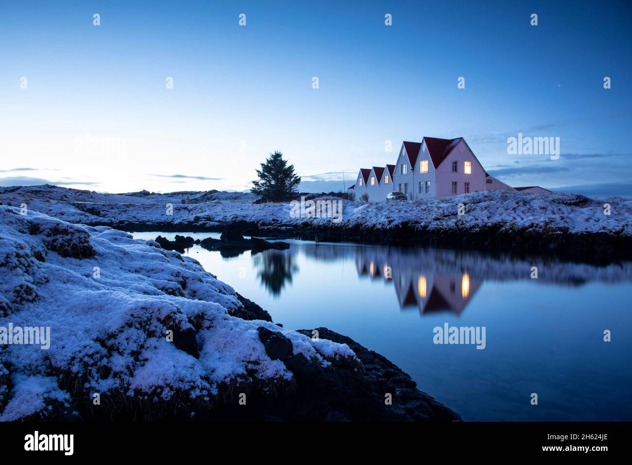 Spiegelung einer Gruppe von Häusern zur blauen Stunde. Stockfoto