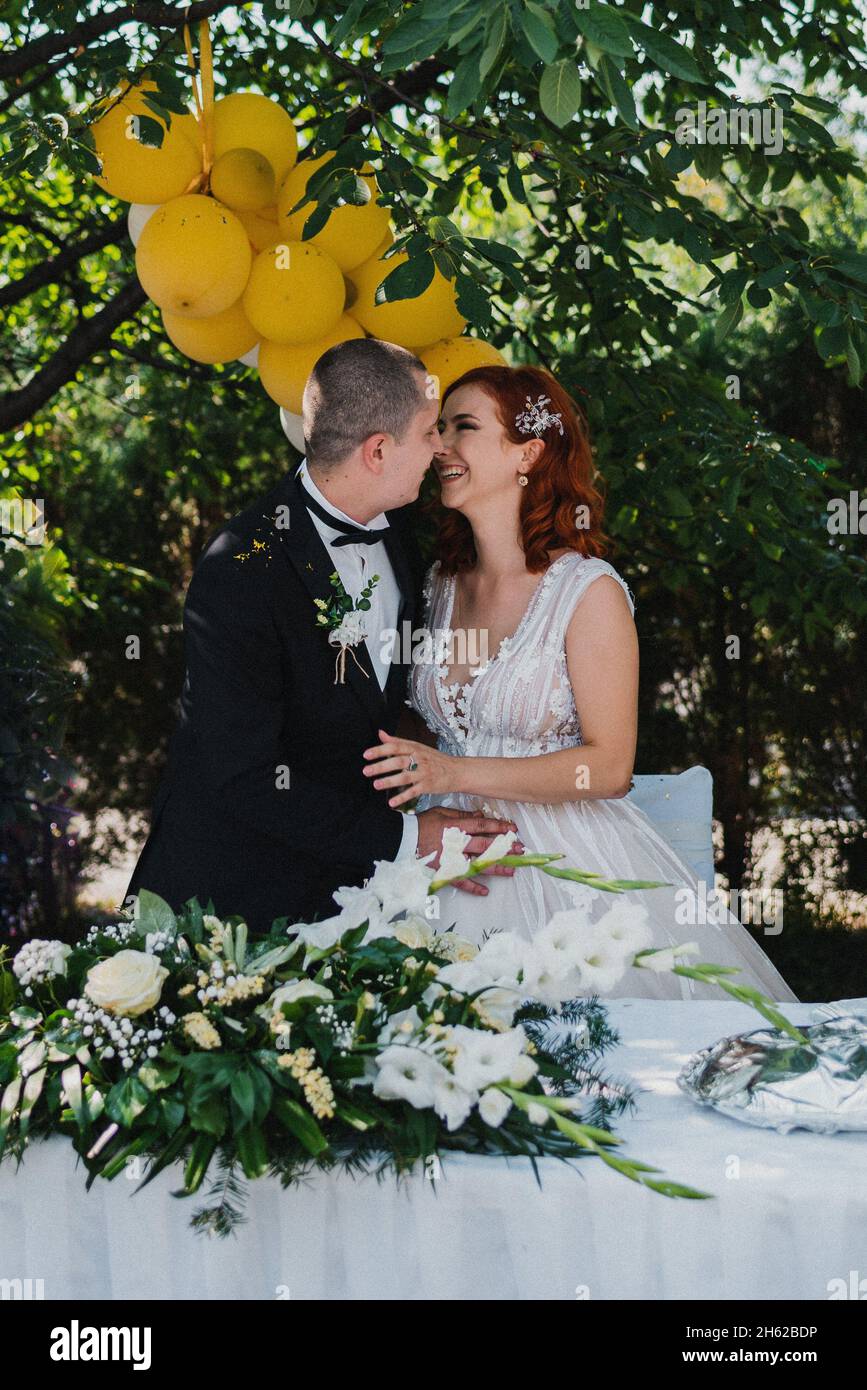 Vertikale Aufnahme eines frisch vermählten Paares, das sich während ihrer Hochzeit am Esstisch umarmt Stockfoto