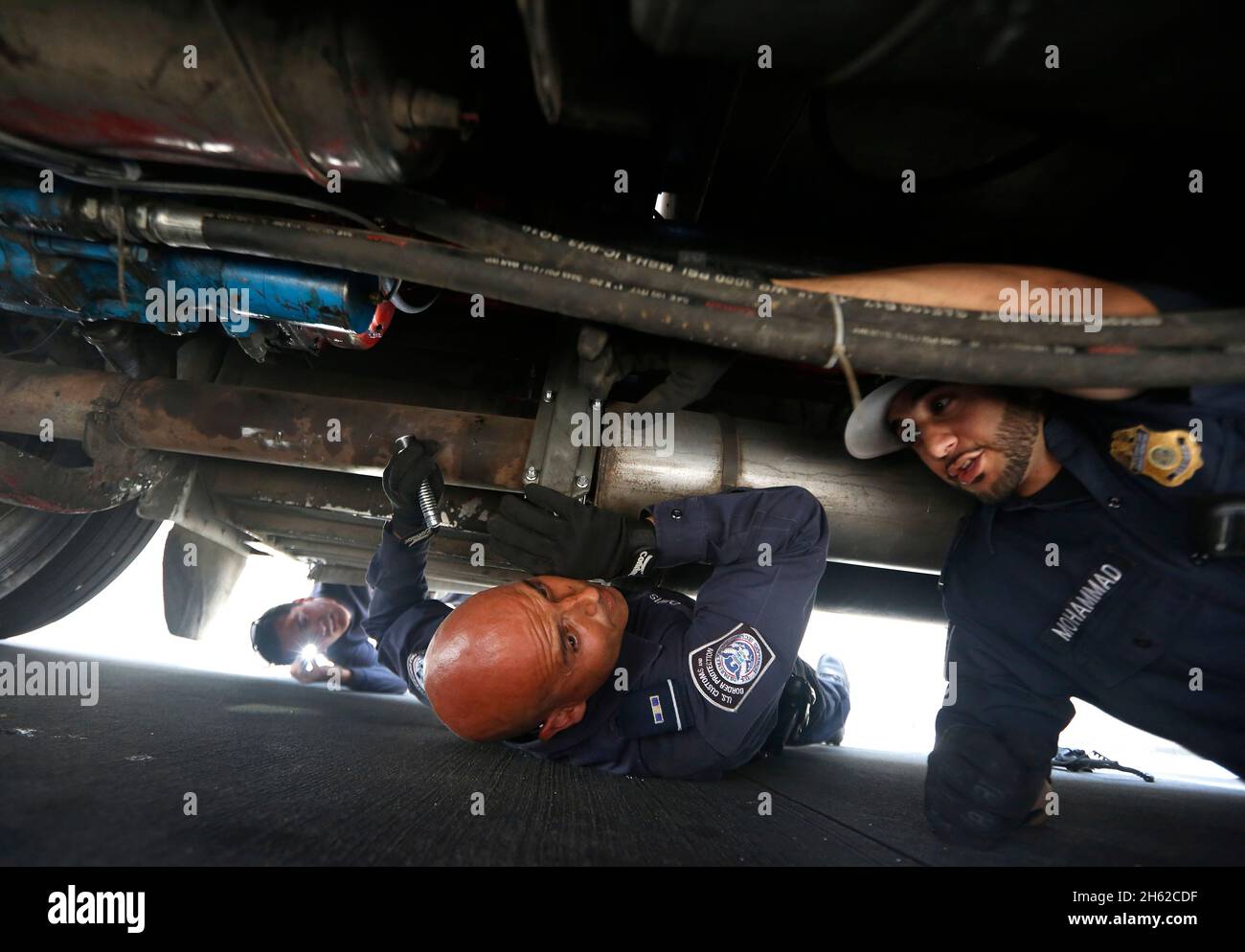 US-Zoll- und Grenzschutzbeamte inspizieren unter einem Traktoranhänger im Hafen von Otay Mesa, Kalifornien, am 23. Juni 2016. Nachdem ein Hund auf merkwürdige Gerüche aus dem Übertragungsbereich des Fahrzeugs zu greifen schien, entschieden die Beamten, dass sie einen genaueren Blick darauf werfen müssten. Stockfoto