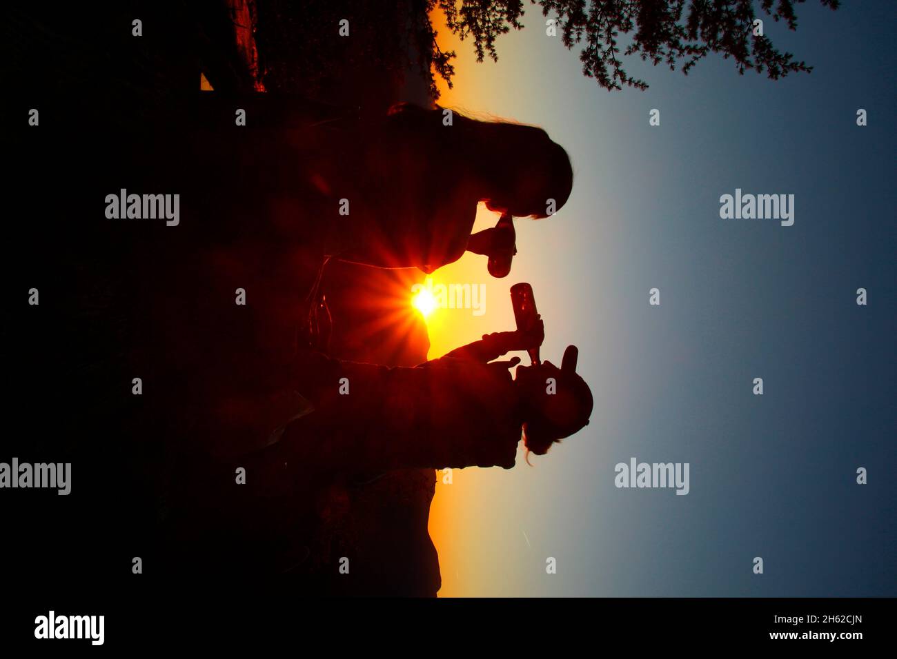 Zwei junge Frauen,Imbiss,Getränk,Flasche Silouette,freuen sich über die Hintergrundbeleuchtung,Sonnenuntergang,fotografiert auf der mittenwalder Hütte am karwendel,mittenwald,oberbayern,isartal,bayern,deutschland,europa, Stockfoto