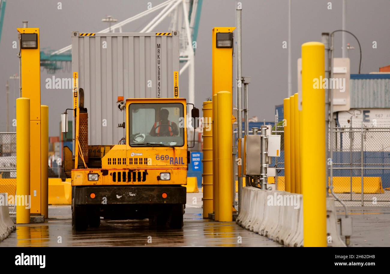 Ein von einem Hafenfahrzeug gezogener Transportcontainer kommt zum Scannen mit auf Lastwagen montierten Strahlungserkennungssystemen an, die von US-Zoll- und Grenzschutzbeamten im Hafen von Miami am 07. Dezember 2015 betrieben werden. Stockfoto