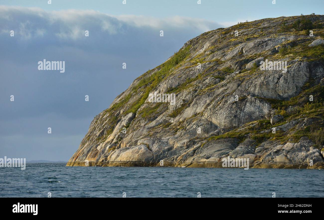 Klippen, die in grüner Vegetation geschnürt sind, ragen ins Meer, während der stellvertretende Verteidigungsminister Bob Work kleine Bootsoperationen in den norwegischen Fjorden bei Bodo, Norwegen, beobachtet, 9. September 2015. Stockfoto