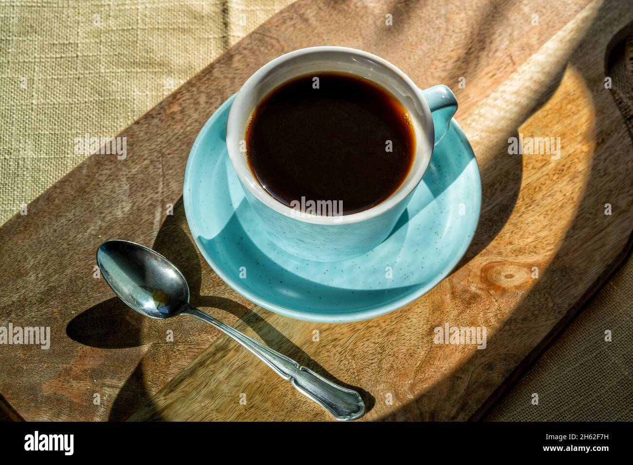 Tasse Kaffee auf einem Brett, das vom Sonnenlicht beleuchtet wird, Herbsttag. Stockfoto