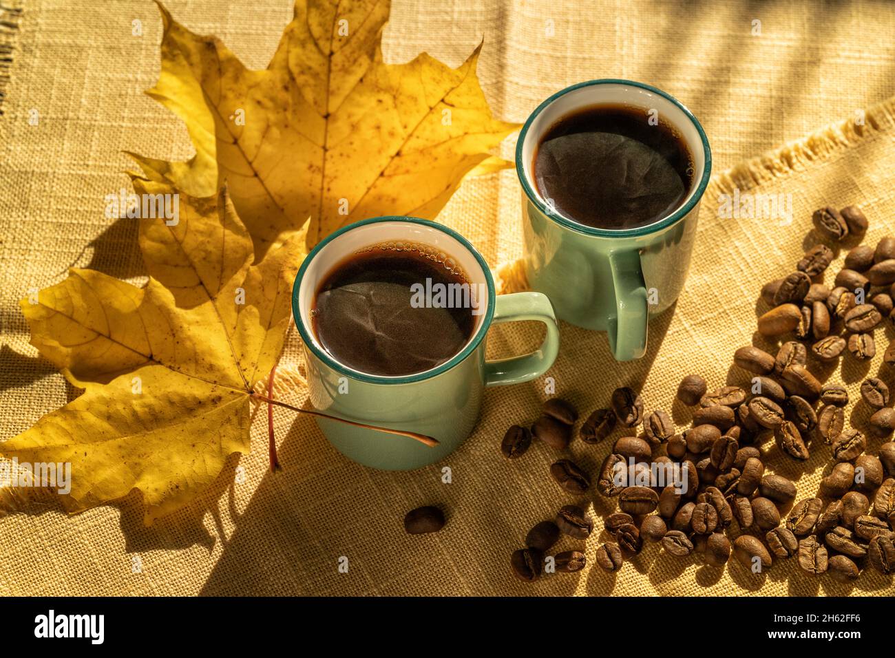 Draufsicht. Tassen Kaffee und Kaffeebohnen, beleuchtet durch Sonnenlicht, Herbsttag. Stockfoto