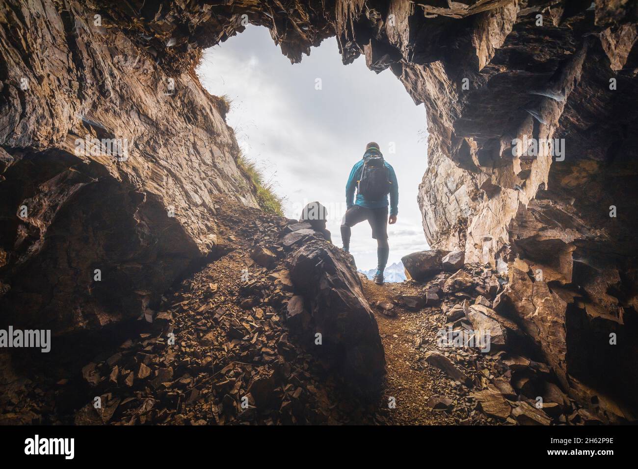 Einsamer Mann,35 - 40 Jahre alt,Wanderer im Hintergrund am Eingang zu einer Höhle in den Bergen,col di lana,dolomites,livinallongo del col di lana,belluno,veneto,italien Stockfoto