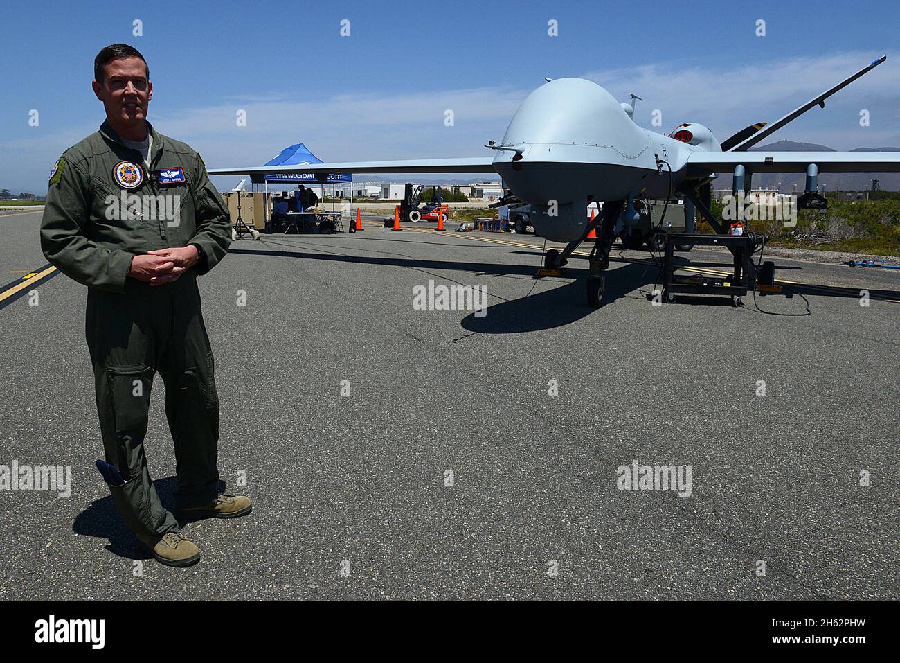 Berichterstattung: Air Force Maj. Scott Gregg, Projektleiter des Black Dart-Projekts, spricht vor einem unbemannten MQ-9-Flugzeugsystem auf dem Marinestützpunkt Ventura County and Sea Range, Point Mugu, Kalifornien, 31. Juli 2015 mit den Medien. Die Drohne, sagte Gregg, fliegt bei mehr als 18,000 Fuß und wiegt mehr als 1,300 Pfund. Es wurde als Teil der zweiwöchigen Black Dart Gegen-UAS-Demonstration vom 26. Juli bis 1. August verwendet, um Technologien, Taktiken und Techniken zu bewerten und zu verbessern, die vom DoD und seinen Partnern verwendet wurden. Stockfoto