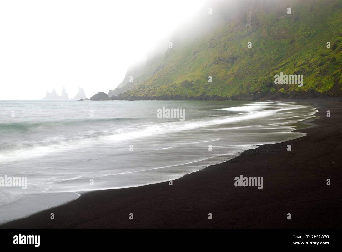 Surfen Sie am schwarzen Strand von Vík í mã½rdal, im Hintergrund die Felsen von reynisdrangar im Nebel, island, Südküste Stockfoto