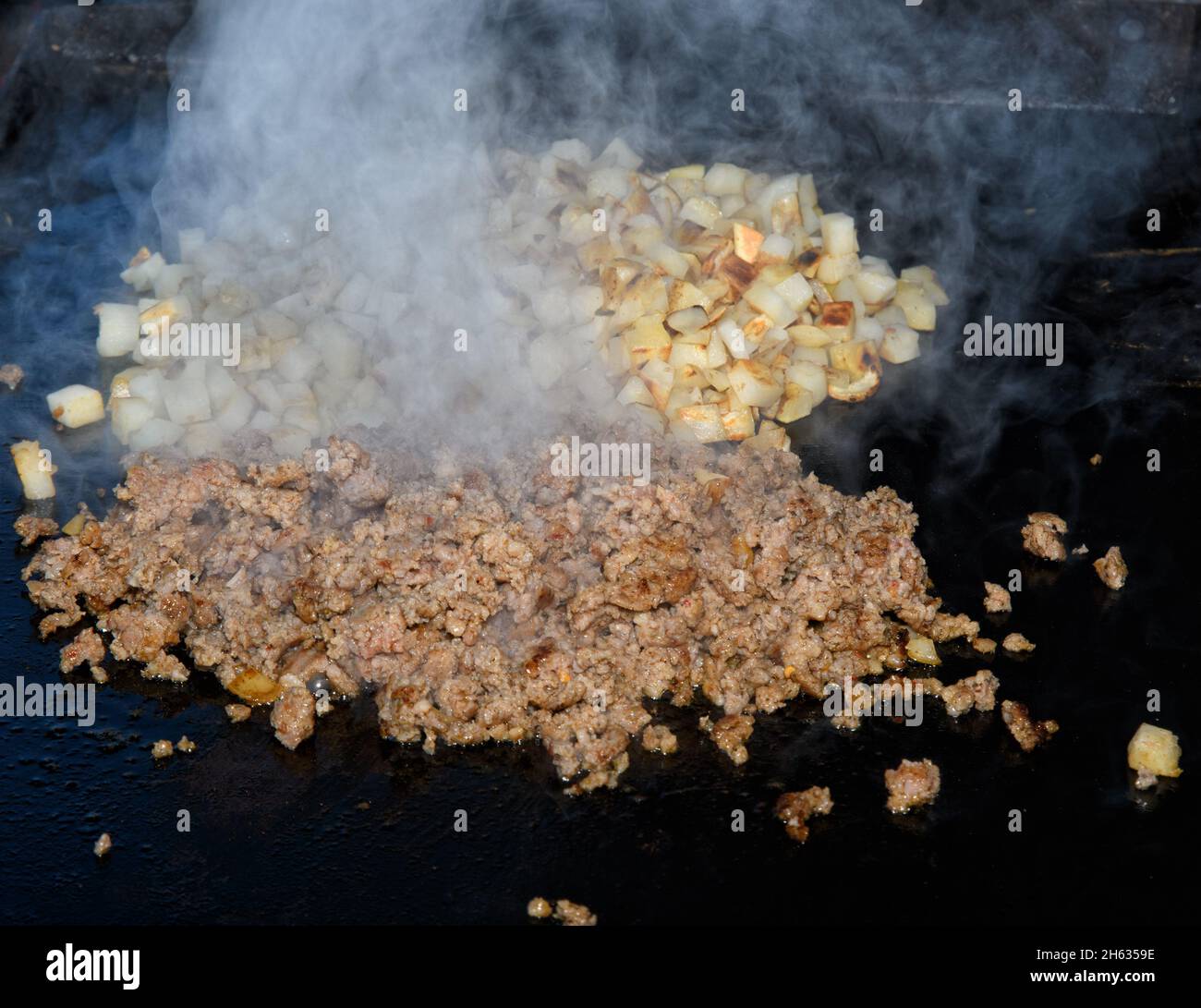 Auf dem Grill kochende Wurst und auf dem Hintergrund ein Röstbraun; aus dem Kochfleisch steigt starker Dampf Stockfoto