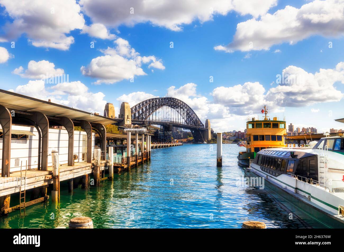 Die Sydney Ferry transportiert NSW an den Kais des Circular Quay mit Blick auf die Sydney Harbour Bridge, die auf dem Wasser schwimmt. Stockfoto