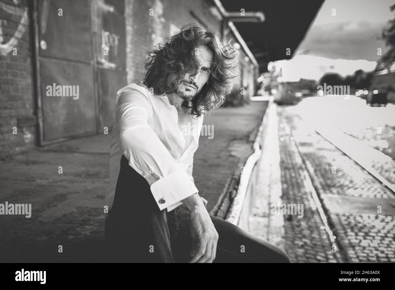 Ein charismatischer Mann mit Bart sitzt auf einem Güterbahnhof Stockfoto