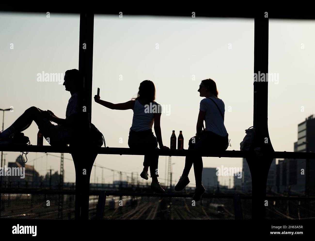 deutschland,bayern,münchen,Hauptbahnhof,hackerbrücke,Jugendliche sitzen auf der eisernen Struktur,chillen,warten auf den Sonnenuntergang,Silhouette Stockfoto