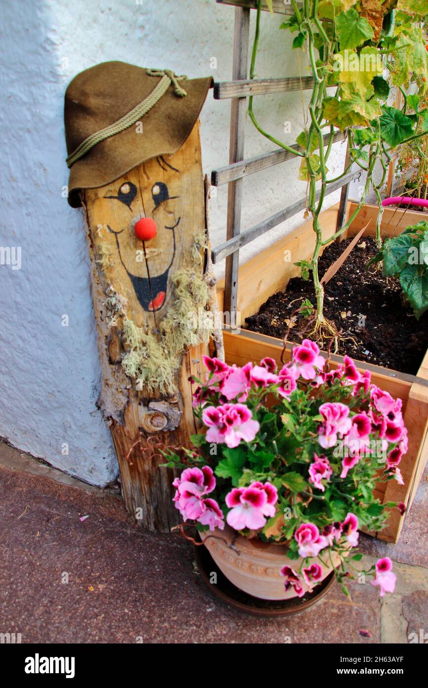 Dekorative Holzfigur mit freundlich lächelndem Gesicht, Hut, Blumen, Pflanze, Trog, Rebe, deutschland, bayern, oberbayern, isartal Stockfoto