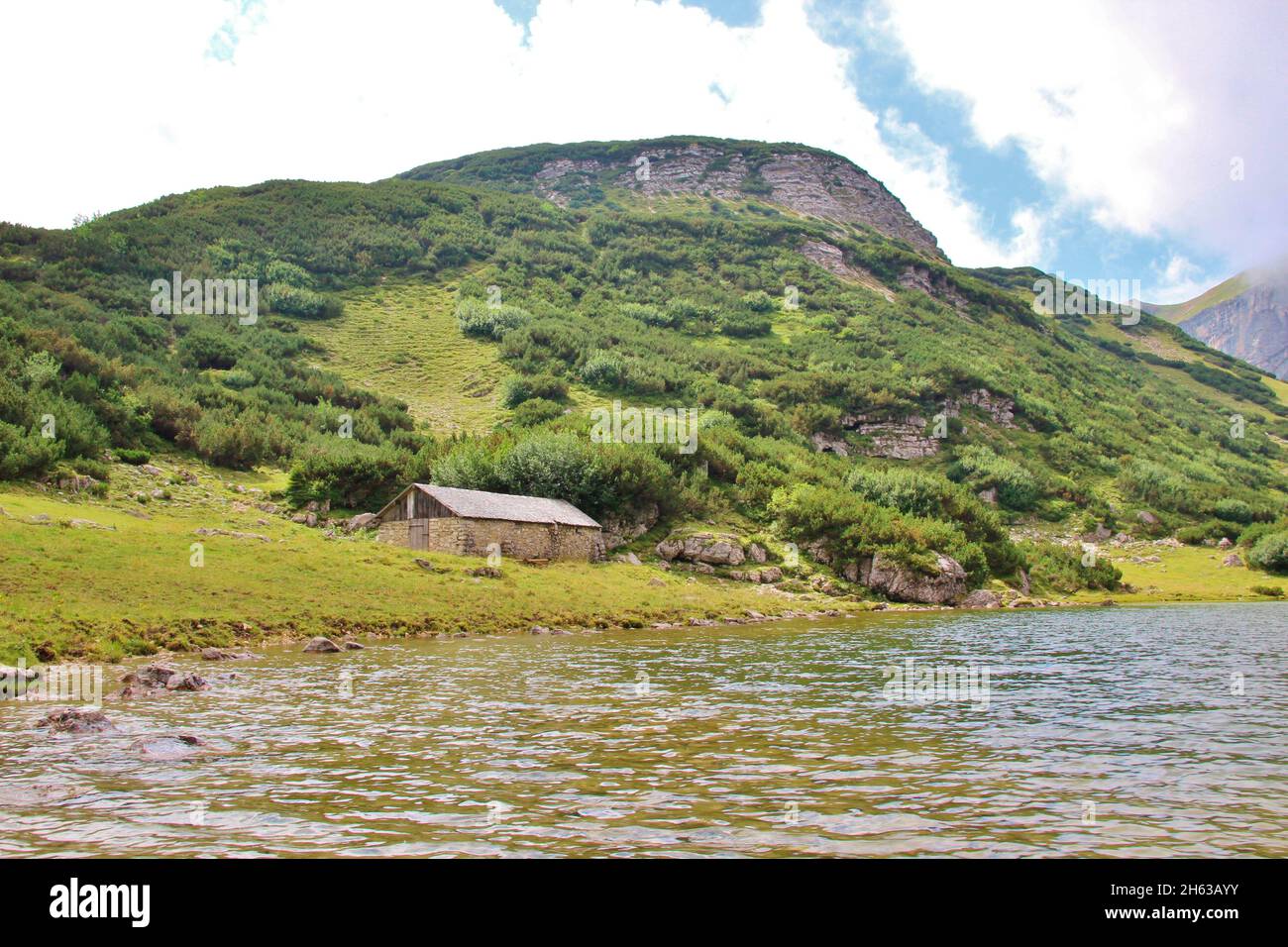 Wanderung zum Zreiner See auf 4 Hektar Bergsee auf 1799 m in den brandenberger alpen,tirol,gemeinde münster,alte Steinmauer-Almhütte mit Schindeldach,im Hintergrund der Latschberg (1949 m) Stockfoto