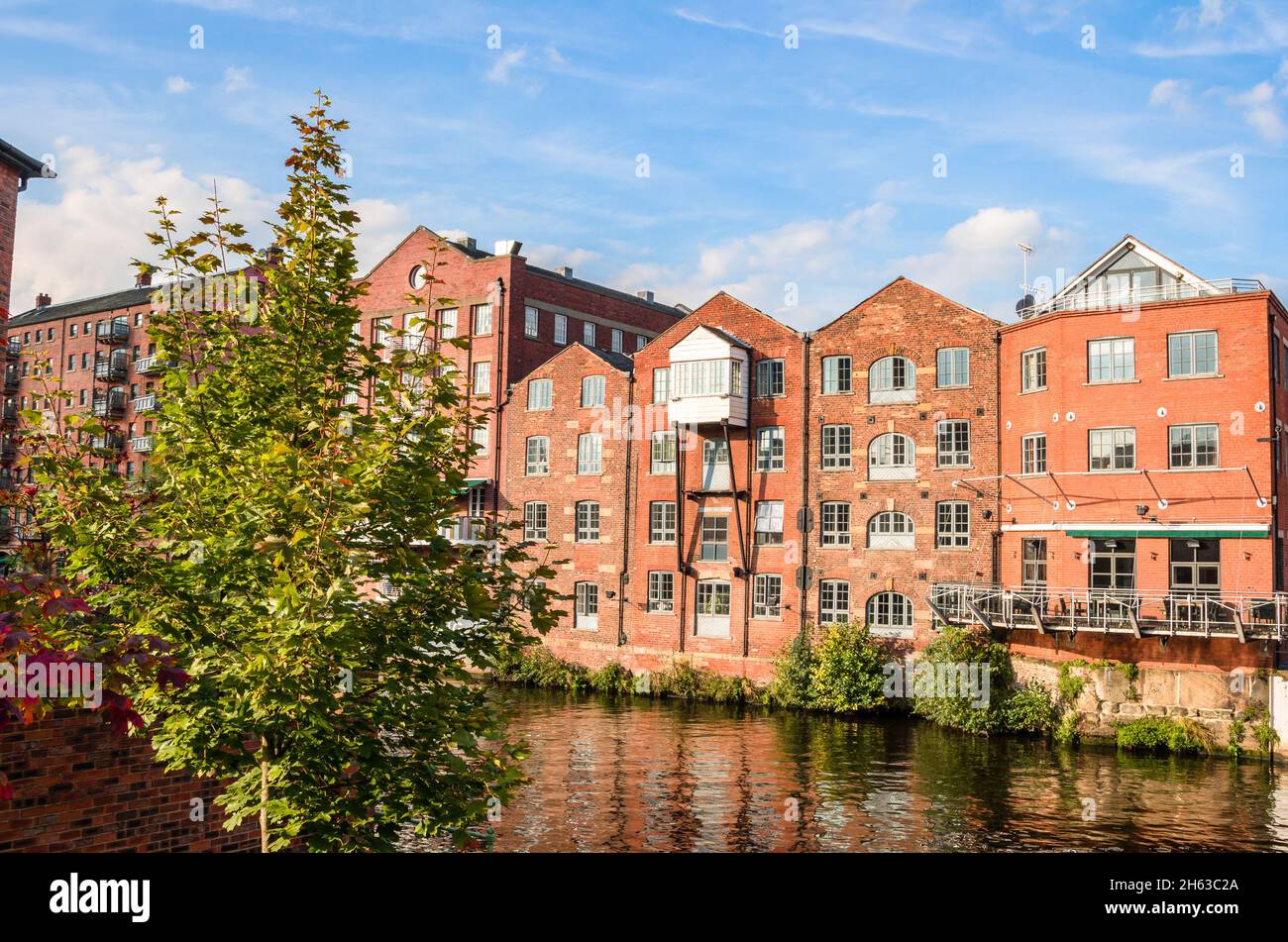 An einem sonnigen Herbsttag wurden alte Lagerhäuser aus Backstein an einem Fluss in Lofts umgewandelt Stockfoto