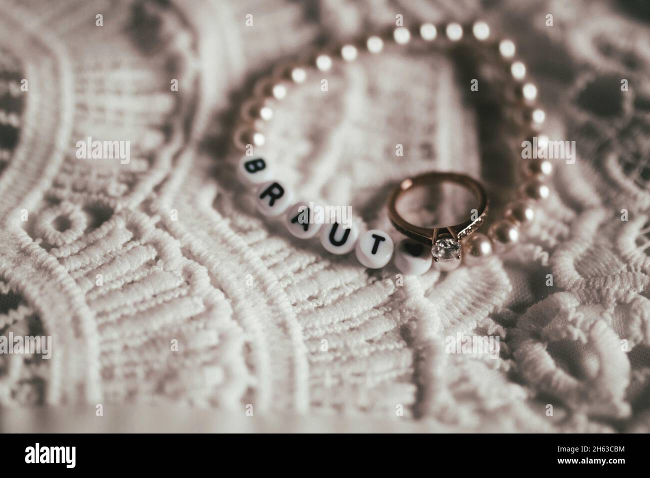 Nahaufnahme von Hochzeitskleid mit diy Armband "Braut" und Verlobungsring Stockfoto