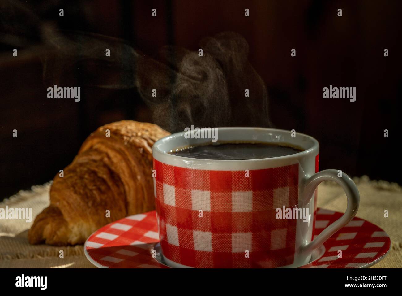 Tasse Kaffee und Croissant auf Serviette Stockfoto