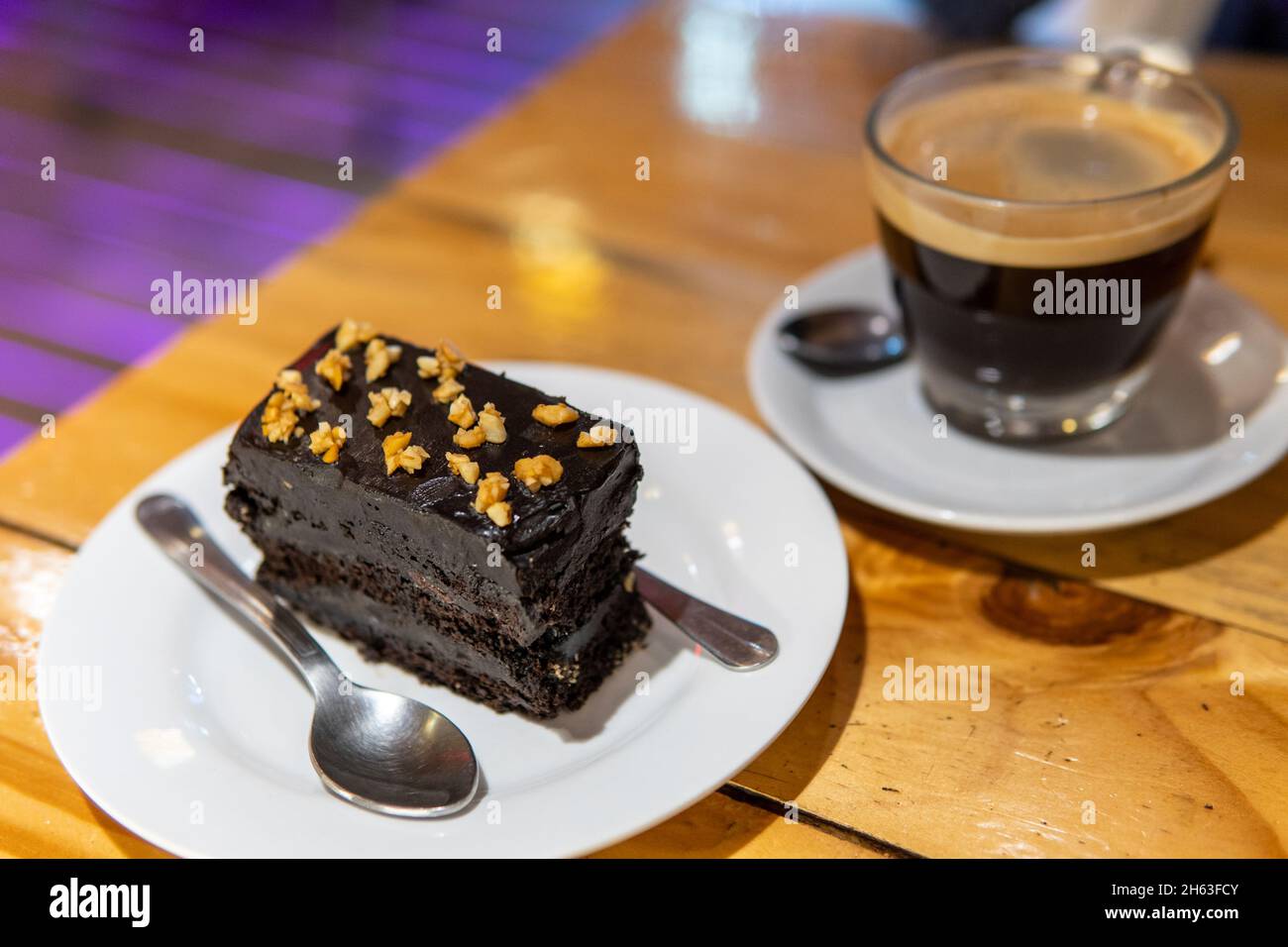Fudgy reichen dunklen Schokolade Kuchen auf Platte mit Kaffee und Löffel Stockfoto