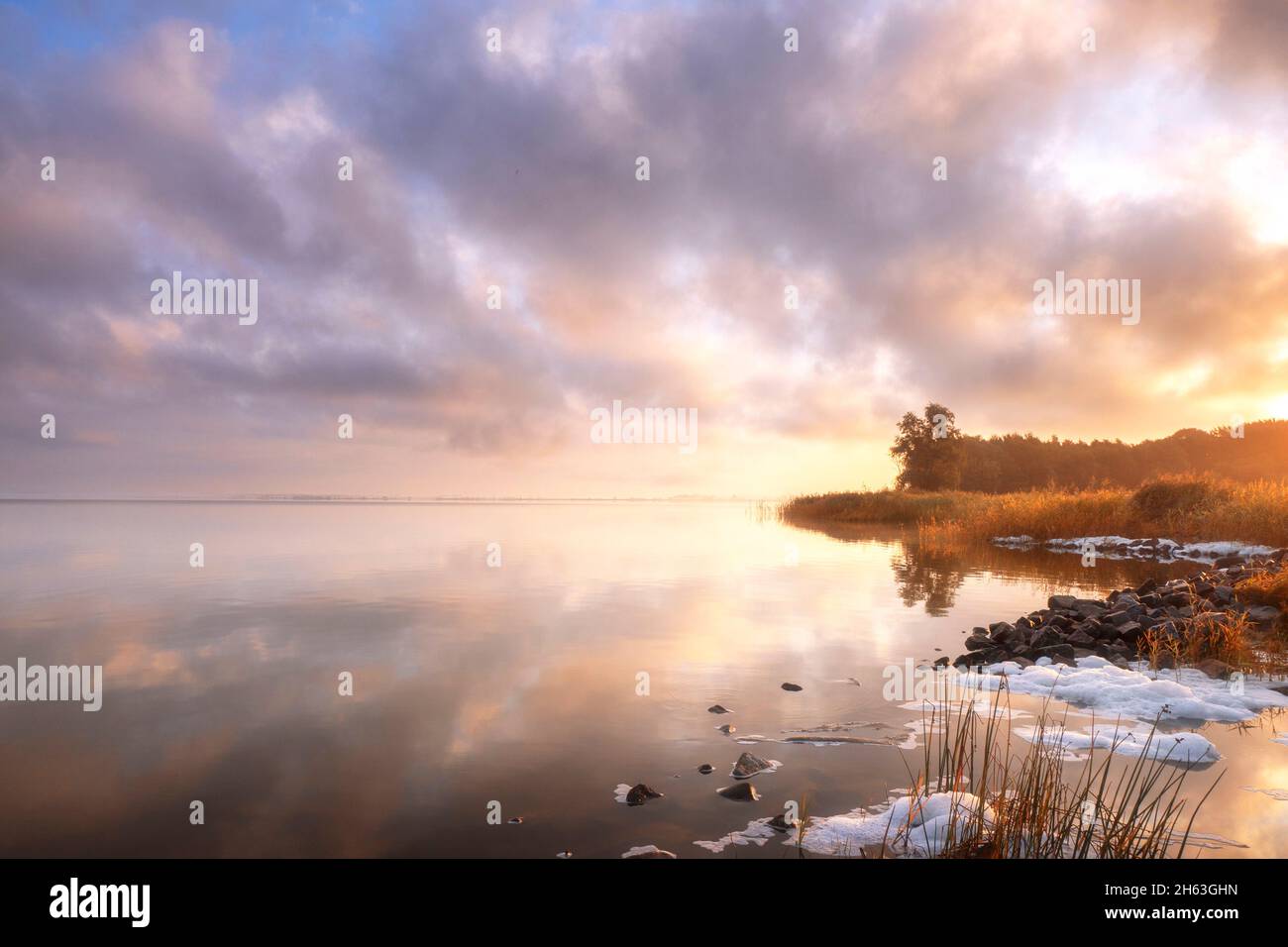 Der Sonnenaufgang auf der Lagune spiegelt sich auf dem glatten Wasser wider Stockfoto