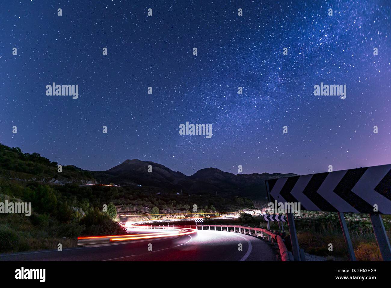 Leichte Spur von Autos auf einer kurvenreichen Straße mit den Sternen oben (milkey way) in andalusien, spanien Stockfoto