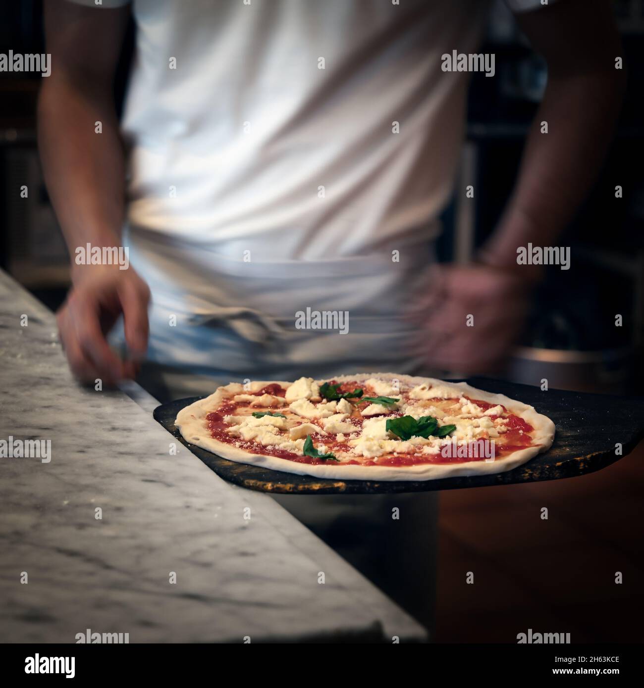 Ein Küchenchef bringt den letzten Schliff für eine Pizza margherita auf den Weg in den Ofen in einer Pizzeria in Kamakura, Japan. Stockfoto
