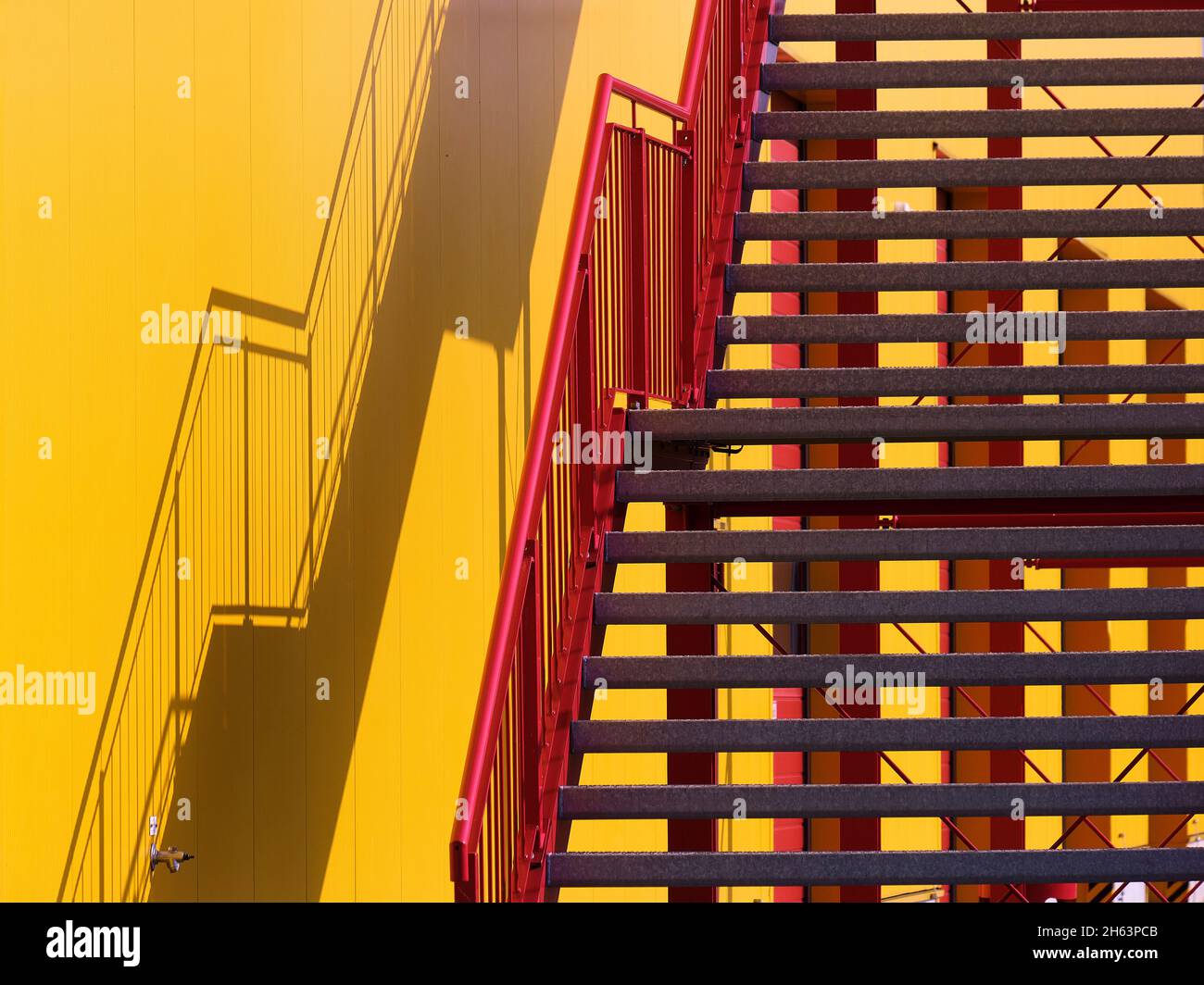 Rote Treppe, gelbes Gebäude, Schatten an der Wand Stockfoto
