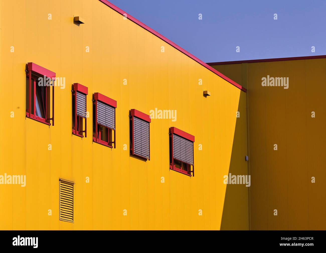 Gelbes Gebäude, rote Fenster, blauer Himmel, Gewerbegebiet, Stockfoto