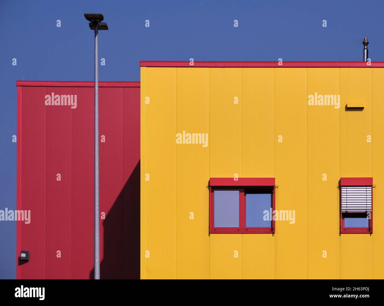 Gelbes Gebäude, rote Fenster, blauer Himmel, Gewerbegebiet, Stockfoto