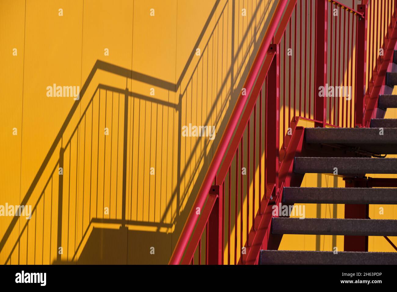 Rote Treppe, gelbes Gebäude, Schatten an der Wand Stockfoto