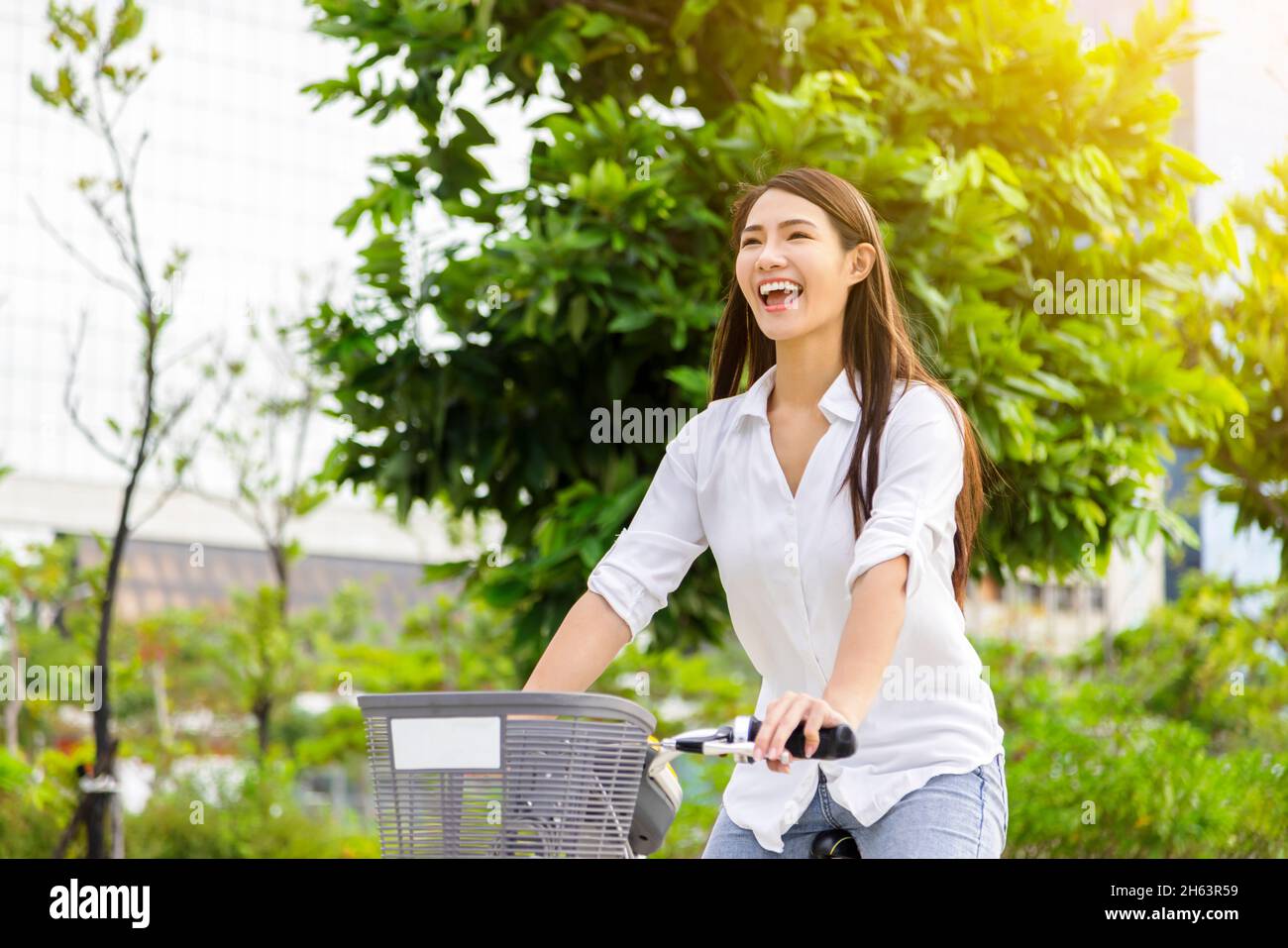 Glückliche junge Frau, die im Stadtpark Fahrrad fährt Stockfoto