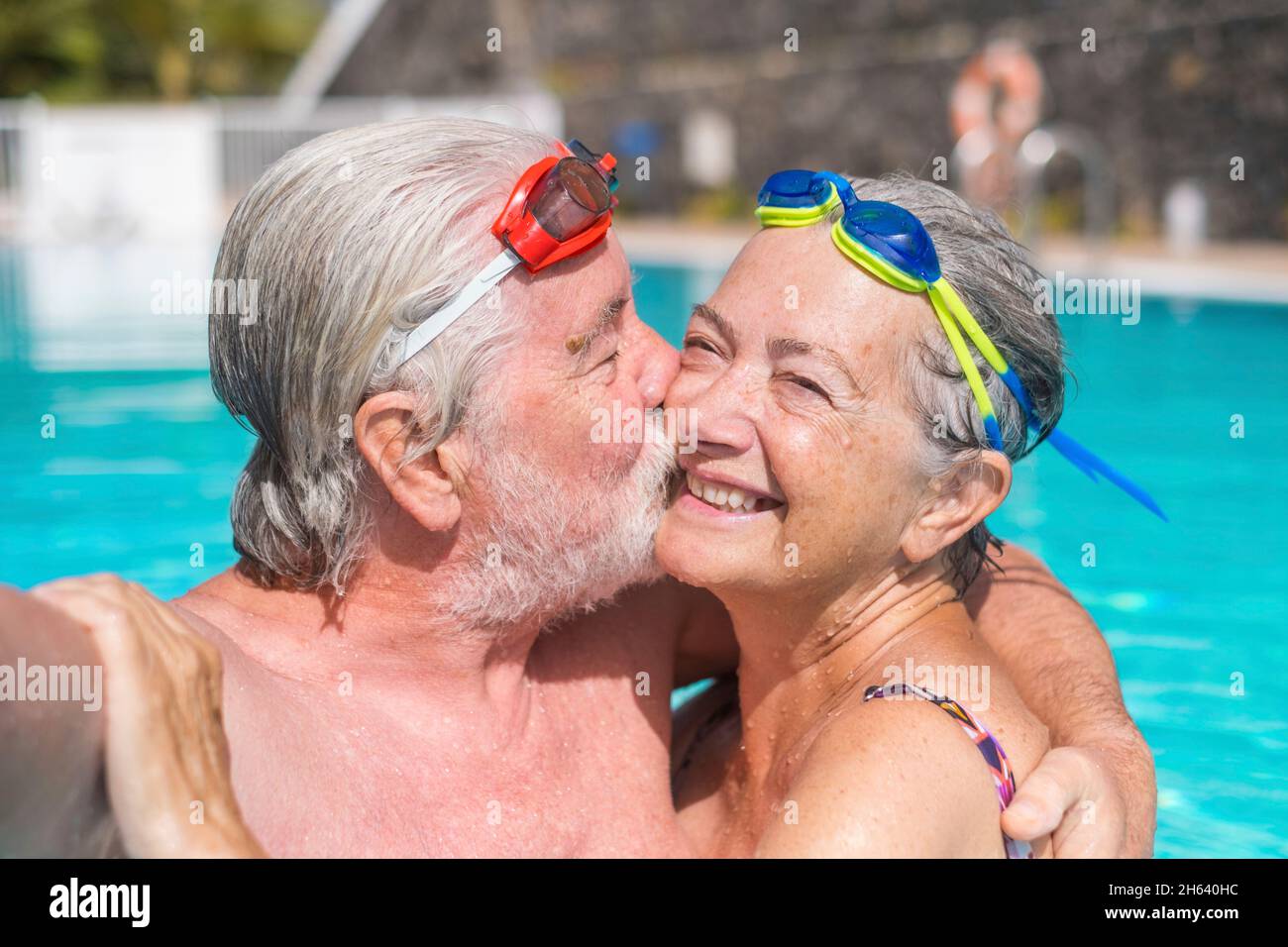 Zwei glückliche Senioren, die Spaß haben und gemeinsam im Schwimmbad ein Selfie-Foto machen, lächeln und auf die Kamera schauen. Glückliche Menschen, die den Sommer draußen im Wasser genießen Stockfoto