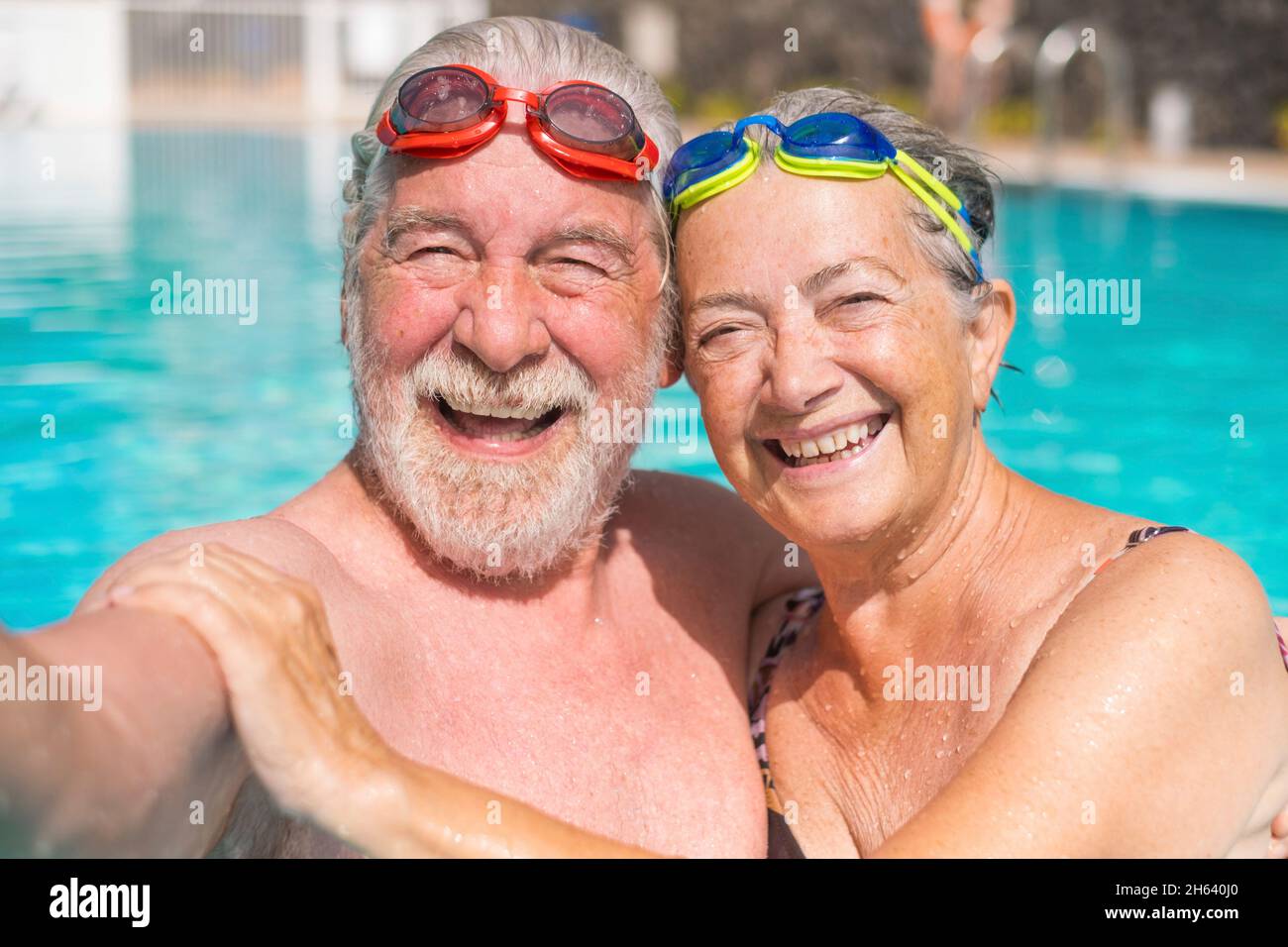 Zwei glückliche Senioren, die Spaß haben und gemeinsam im Schwimmbad ein Selfie-Foto machen, lächeln und auf die Kamera schauen. Glückliche Menschen, die den Sommer draußen im Wasser genießen Stockfoto