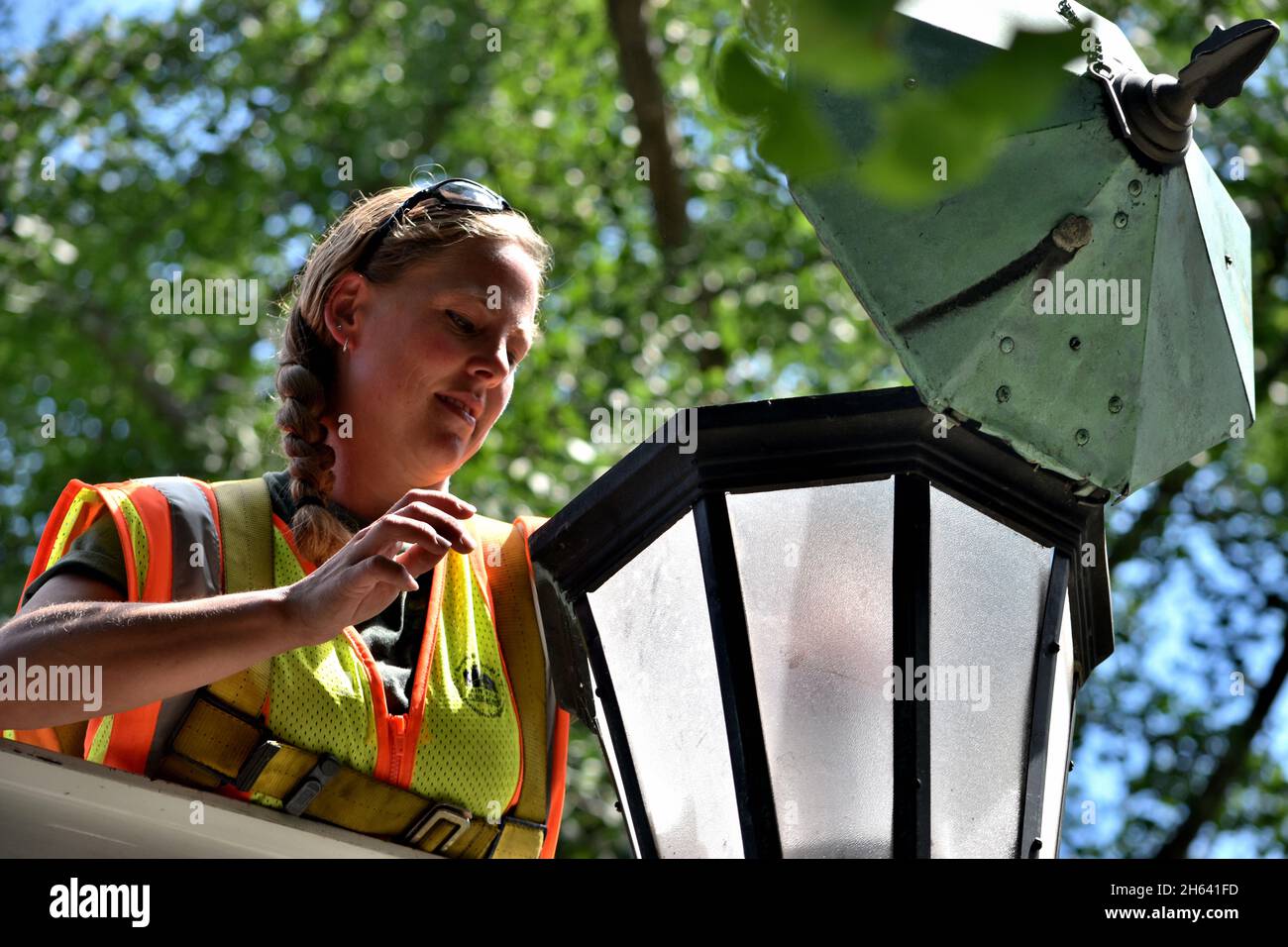 Die Dame des öffentlichen Werks von St. Paul ersetzt die Straßenlampe durch eine LED-Leuchte. Stockfoto