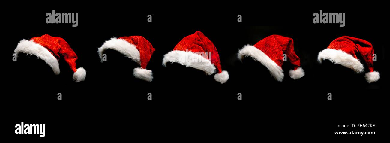 Rote weihnachtsmützen isoliert vor schwarzem Hintergrund Stockfoto