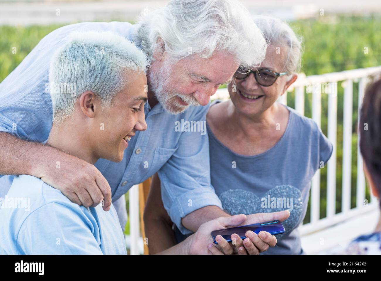 Großeltern mit Enkel mit Blick auf Handy. Glückliche Multi-Generation-Familie Blick auf die Rückseite eines Mobiltelefons Gerät. Stockfoto