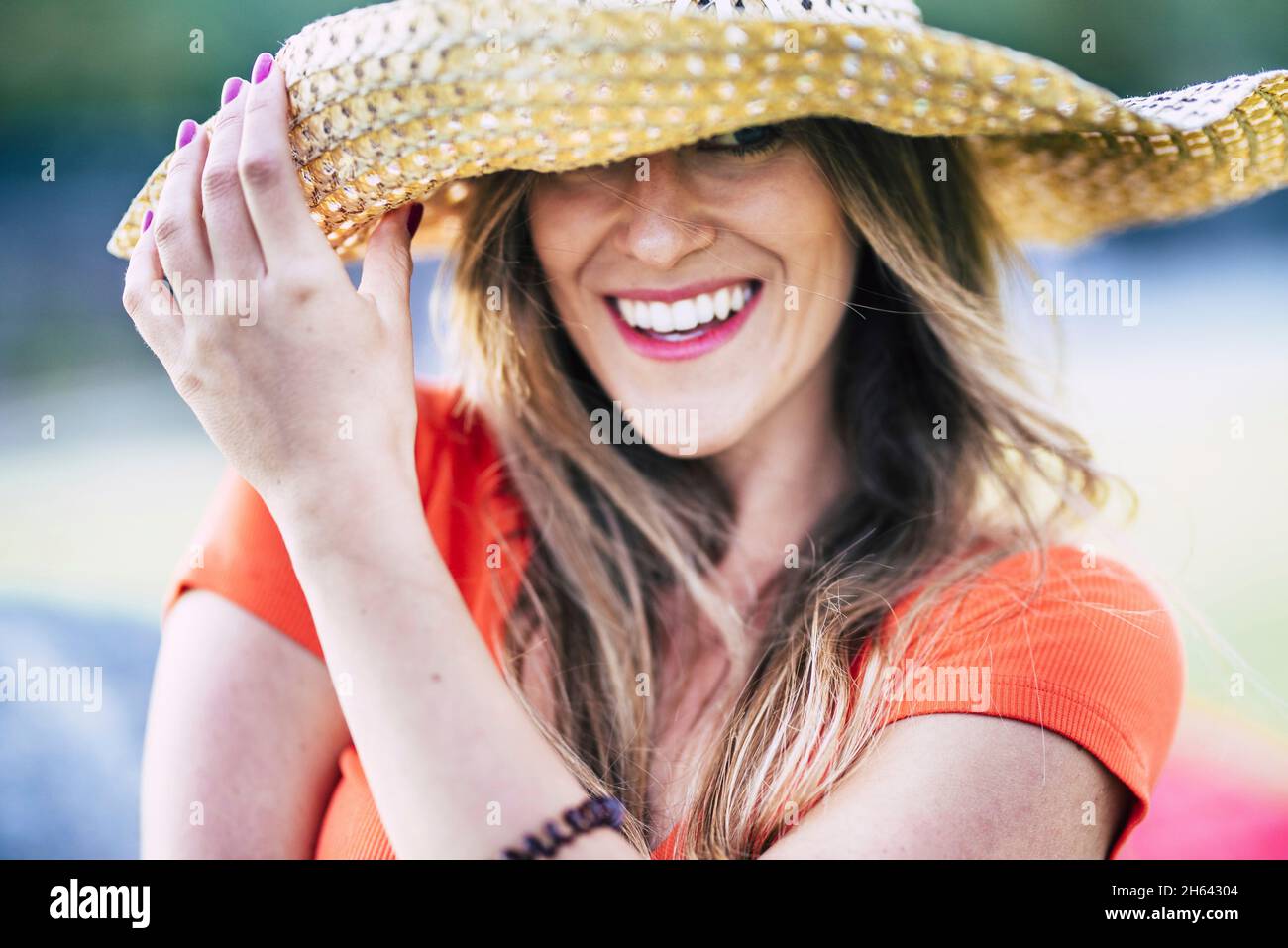 Portrait der schönen jungen Frau lächelnd, während sie ihren stilvollen Strohhut im Freien im Urlaub. Glückliche weibliche Tourist posiert im Freien in Hut während der Sommerferien Stockfoto Portrait der schönen jungen Frau lächelnd, während sie ihren stilvollen Strohhut im Freien im Urlaub. Glückliche weibliche Tourist posiert im Freien in Hut während der Sommerferien Stockfoto