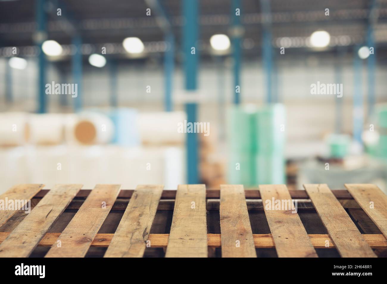 Verwischen Sie die Lagerzone des Rohstofflagers mit dem Holzpalettenboden im Vordergrund für die Werbemontage im Hintergrund Stockfoto