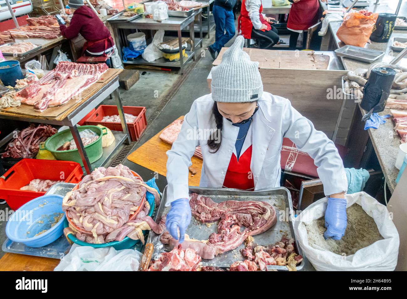 Eine kasachische Frau, die salzigen Knoblauch auf Pferdefleisch legt, um Qazy, Pferdewurst zuzubereiten. Fleischmarkt in Altyn Orda, Almaty, Kasachstan Stockfoto