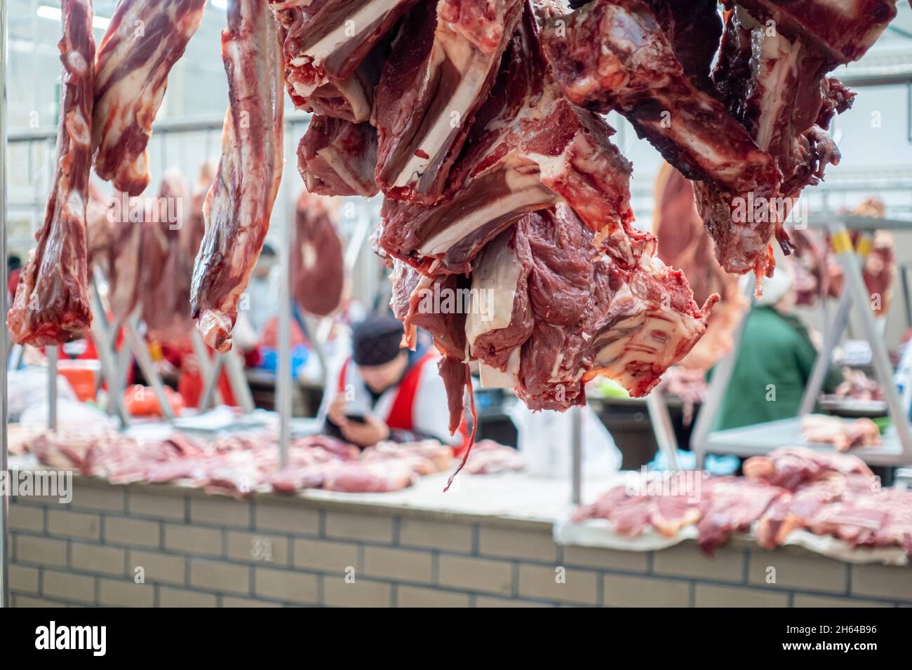 Aufgehängtes rohes Fleisch, das auf dem Altyn Orda-Markt, dem größten Markt in Almaty, Kasachstan, verkauft wird Stockfoto